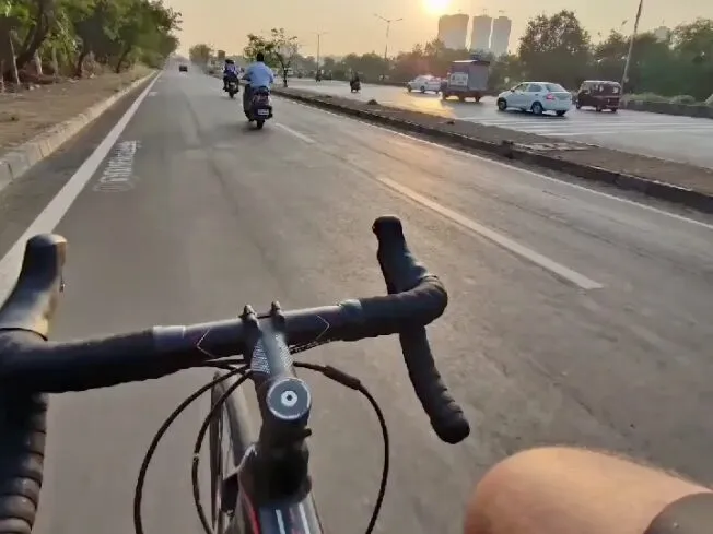 A rider’s view over the handlebars, down a wide road at dawn.